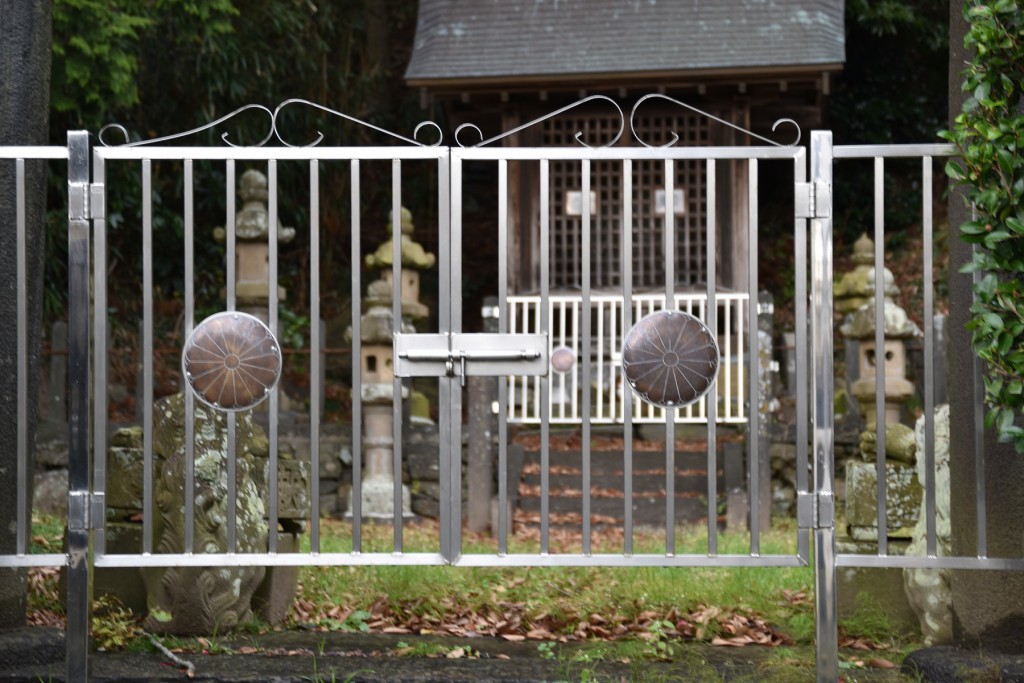 皇室の菊家紋がほどこされた門の奥に祠がある